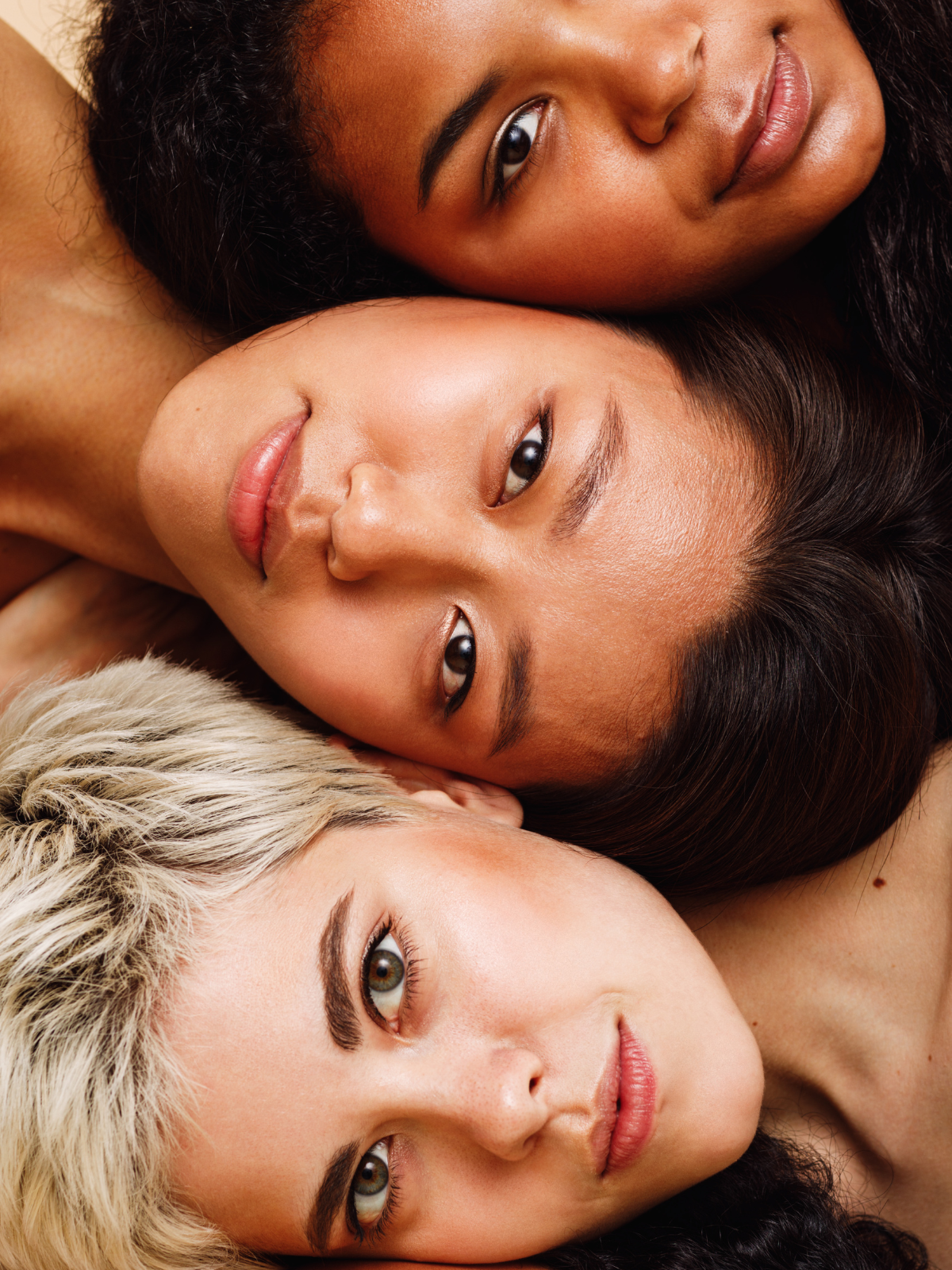 Three women lying down with their heads together